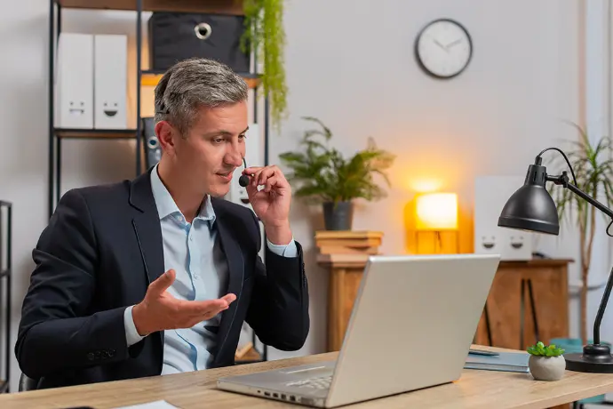 Illustration of an employer attending a video call while working on a laptop as part of recruitment and professional inclusion support