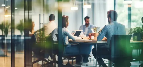 Employees gathered around a meeting table collaborate in a modern workspace
